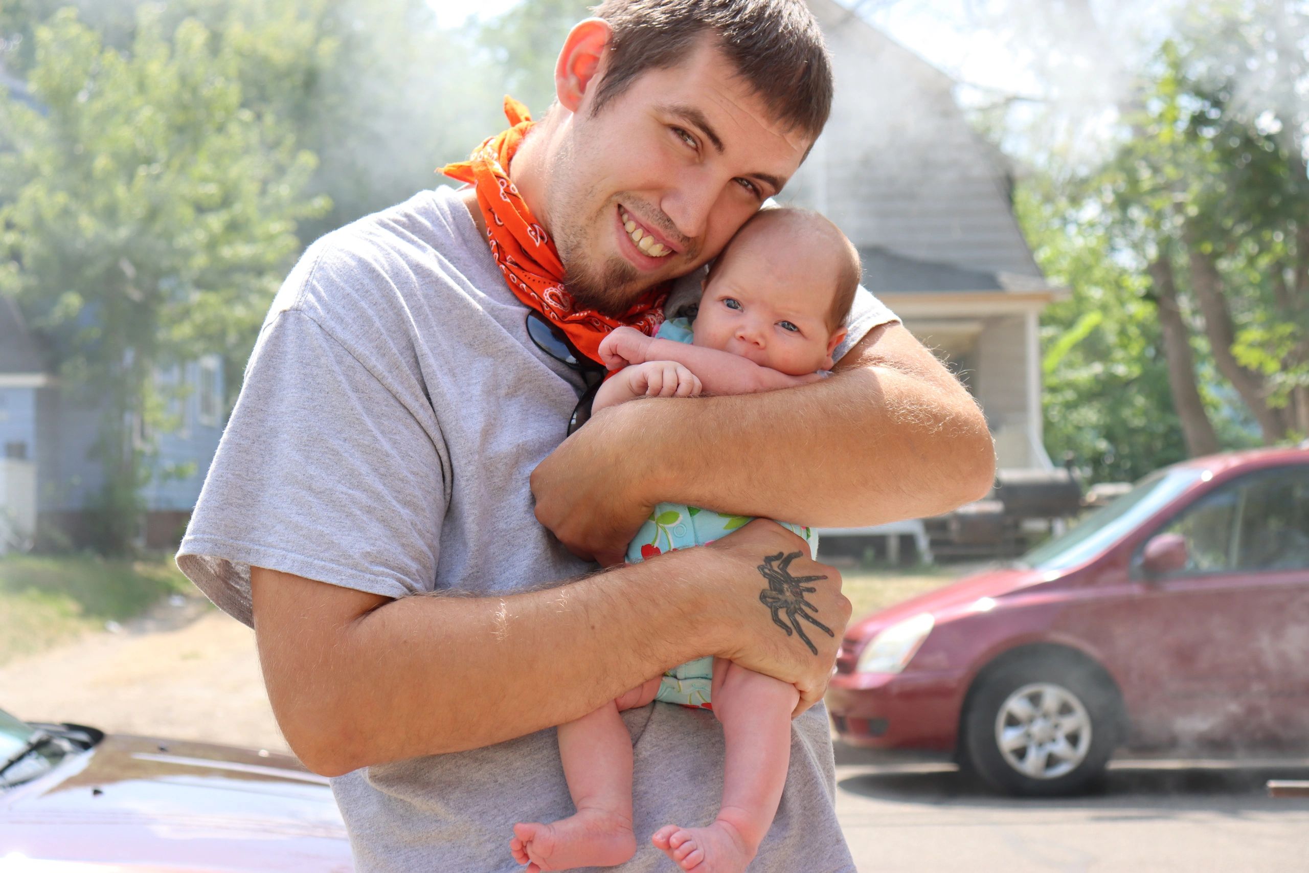 Man holding infant in driveway