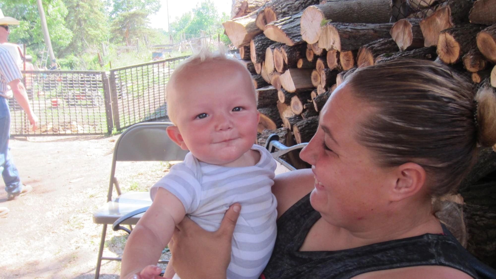 Woman holding infant at farm setting